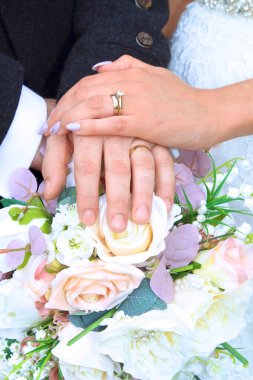 Gelin ve damat yüzük çekimleri. Elleri bir demet çiçeğe yerleştirilmiş.