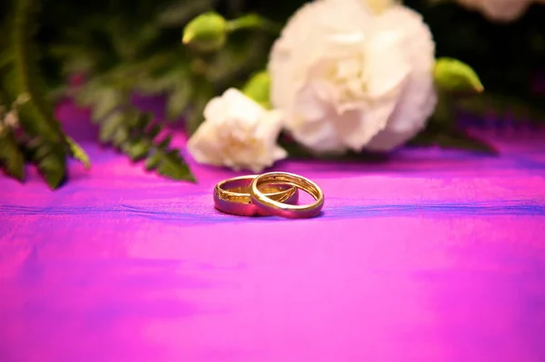 gold wedding rings against purple background