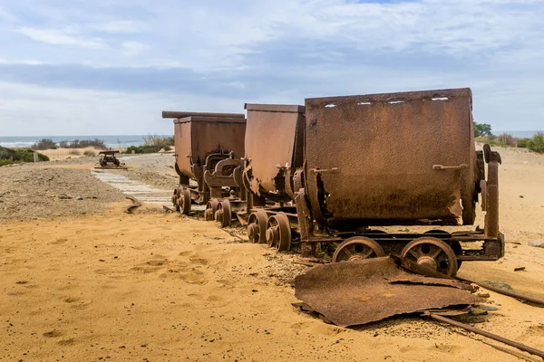 Old and rusty mine carts in the open air on the sand in Sardinia. Ingortosu\'s mine