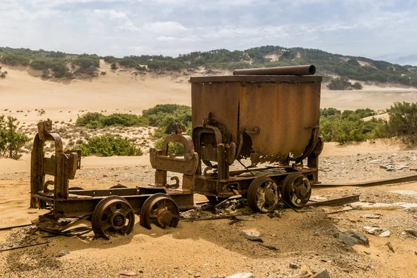 Old and rusty mine carts in the open air on the sand in Sardinia. Ingortosu\'s mine