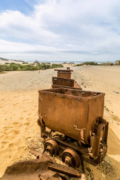 Old and rusty mine carts in the open air on the sand in Sardinia. Ingortosu\'s mine. Arbus, Cagliari