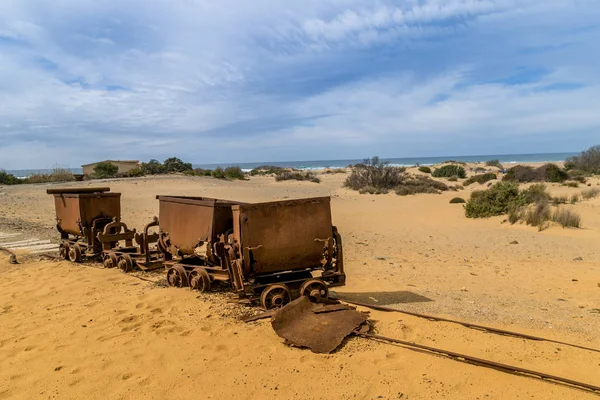 Old and rusty mine carts in the open air on the sand in Sardinia. Ingortosu\'s mine. Arbus, Cagliari