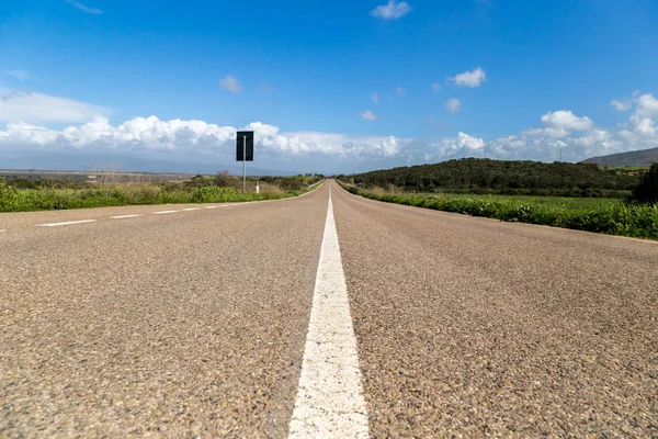 青い空と春の雲と緑の野原をまっすぐアスファルトの道路 サルデーニャ国 ロイヤリティフリーのストック画像