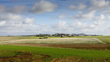 Kırsal kesimde bir köy. Bulutlu tarlalar ve gökyüzü