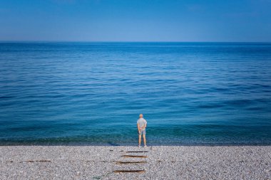 Sahilde yalnız bir adam ufukta görünüyor.