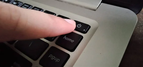 Kişi bir dizüstü bilgisayarın güç düğmesine basacak.