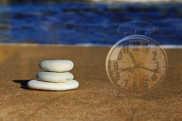 海を背景に砂の上に3つの小石と時計 — ストック写真