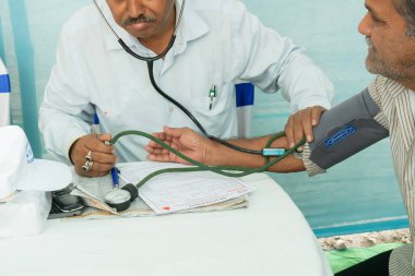 Kolkata, Batı Bengal, Hindistan - 25 Şubat 2018: Hintli Doktor, tıbbi aletleri olan bir hastanın kan basıncını kontrol ediyor.