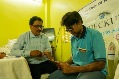 Kolkata, Batı Bengal, Hindistan - 25 Şubat 2018: Hintli erkek doktor, Hintli bir erkek hastanın gözünü test ediyor, Göz Test Kampı.