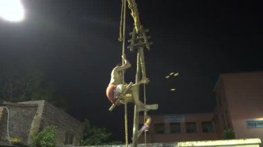 Howrah, Batı Bengal, Hindistan - 15 Nisan 2019: İplerden sarkan iki Hindu hayranı gece aşağıda izleyiciler üzerinde havada daireler çiziyor. Bengali Yeni Yılı için Hindu gajon festivali ritüeli.