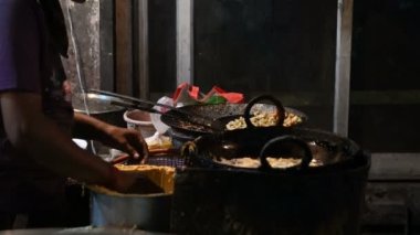 Mirchi Bada, akşamları yol kenarında bir sokak yemeği satıcısı tarafından kızartma tavasında kızartılıyor. Jodhpur, Rajasthan, Hindistan 'da çekildi..