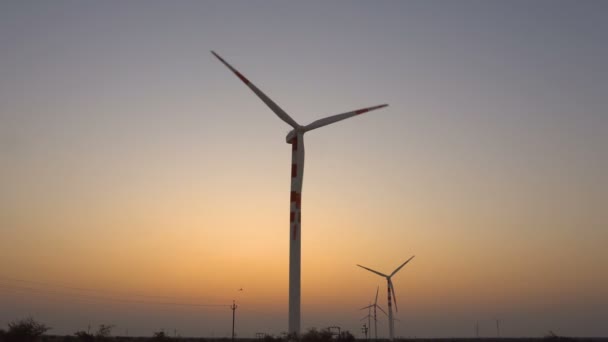 風力発電所はインドのラジャスタン州ジャイサルマーのタール砂漠で発電している 背景にオレンジ色の空で夜明けに撮影 — ストック動画