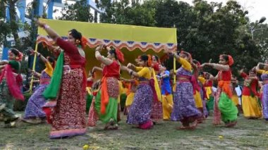 Kolkata, Batı Bengal, Hindistan - 10 Mart 2020: Renkli Hint elbiseleri giymiş neşeli genç Bengalli kız dansçılar, Dol utsab veya Holi festivalinde dans ediyorlar. Hindistan 'da bahar kutlaması. 4K görüntü.