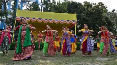 Kolkata, Batı Bengal, Hindistan - 10 Mart 2020: Renkli Hint elbiseleri giymiş gülümseyen Bengalli kız dansçılar, Dol utsab veya Holi festivalinde dans ediyorlar. Hindistan 'da bahar kutlaması. 4K.