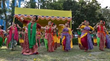 Kolkata, Batı Bengal, Hindistan - 10 Mart 2020: Renkli Hint elbiseleri giymiş gülümseyen Bengalli kız dansçılar, Dol utsab veya Holi festivalinde dans ediyorlar. Hindistan 'da bahar kutlaması. 4K.
