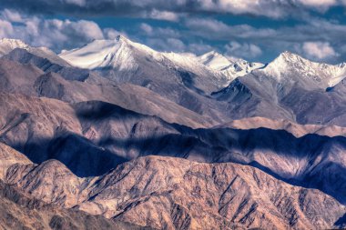 Arka planda buz zirveleri, bulutlu mavi gökyüzü, Ladakh, Jammu ve Kashmir 'in Rocky manzarası, Hindistan