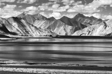 Pangong Tso (Göl) 'deki dağların mavi gökyüzü üzerindeki yansımaları ve kayaları. Ladakh 'ta Hindistan' dan Tibet 'e kadar uzanan büyük bir göldür. Leh, Ladakh, Jammu ve Kashmir, Hindistan. Siyah ve beyaz stok görüntüsü.