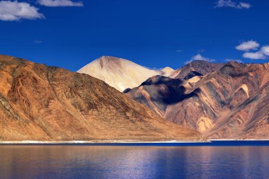 Pangong tso 'daki dağların yansıması (Göl) ve arka planda mavi gökyüzü. Ladakh 'ta büyük bir göl olup Hindistan' dan Tibet 'e kadar 134 km uzunluğundadır. Leh, Ladakh, Jammu ve Kashmir, Hindistan