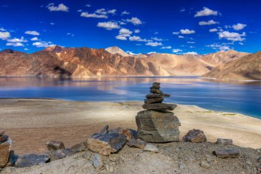 Pangong Tso (Göl) 'deki dağların mavi gökyüzü üzerindeki yansımaları ve kayaları. Ladakh 'ta büyük bir göl olup Hindistan' dan Tibet 'e kadar 134 km uzunluğundadır. Leh, Ladakh, Jammu ve Kashmir, Hindistan