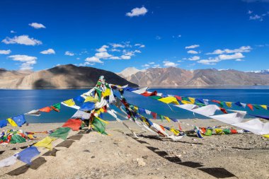 Pangong Tso Gölü 'nde Budist dua bayrakları dalgalanıyor. Himalayalar 'da 4,350 m (14,270 ft) yüksekliğinde büyük bir göldür. 134 km uzunluğundadır ve Hindistan 'dan Tibet' e kadar uzanır..