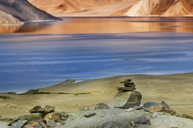 Pangong Tso (Göl) 'deki dağların mavi gökyüzü üzerindeki yansımaları ve kayaları. Ladakh 'ta büyük bir göl olup Hindistan' dan Tibet 'e kadar 134 km uzunluğundadır. Leh, Ladakh, Jammu ve Kashmir, Hindistan