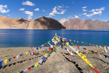 Pangong Tso Gölü 'nde Budist dua bayrakları dalgalanıyor. Himalayalar 'da 4,350 m (14,270 ft) yüksekliğinde büyük bir göldür. 134 km uzunluğundadır ve Hindistan 'dan Tibet' e kadar uzanır..