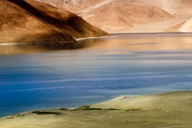 Pangong Tso (Göl) 'deki dağların mavi gökyüzü üzerindeki yansımaları ve kayaları. Ladakh 'ta büyük bir göl olup Hindistan' dan Tibet 'e kadar 134 km uzunluğundadır. Leh, Ladakh, Jammu ve Kashmir, Hindistan