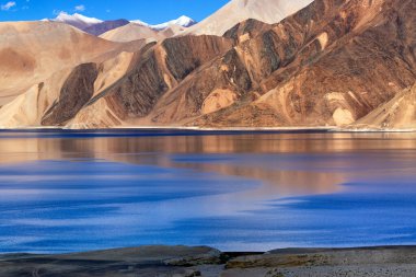Pangong Tso (Göl) 'deki dağların güzel bir yansıması. Arka planda mavi gökyüzü var. Ladakh 'ta büyük bir göl olup Hindistan' dan Tibet 'e kadar 134 km uzunluğundadır. Leh, Ladakh, Jammu ve Kashmir, Hindistan