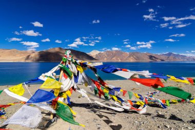 Pangong Tso Gölü 'nde Budist dua bayrakları dalgalanıyor. Himalayalar 'da 4,350 m (14,270 ft) yüksekliğinde büyük bir göldür. 134 km uzunluğundadır ve Hindistan 'dan Tibet' e kadar uzanır..