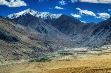 Arka planda buz zirveleri, bulutlu mavi gökyüzü, Ladakh, Jammu ve Kashmir 'in Rocky manzarası, Hindistan