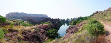 Rao Jodha çölündeki Jodhpur, Hindistan 'dan Mehrangarh kalesinin panoramik manzarası. Önde bir göl, arkada Mehrangarh kalesi ve çöl parkının kayalık manzarası..