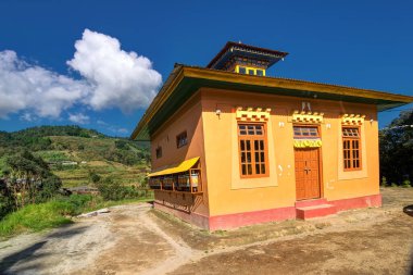 Sikkim, Hindistan 'daki Okhrey Köyü' nde güneşli bir Budist Manastırı. Yukarıda mavi bulutlu gökyüzü ve arkada Himalaya Dağları.