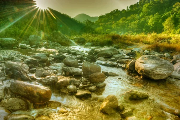 Beautiful Reshi River water flowing on rocks at dawn,  Sikkim, India - sun rays at the background falling on water making spectacular view , tinted image