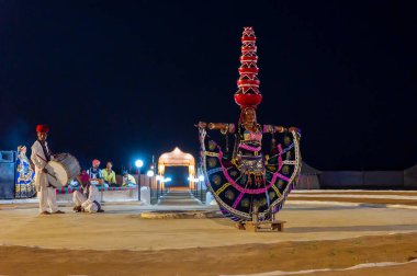 Thar Çölü, Rajasthan, Hindistan - 15 Ekim 2019: Bir halk dansçısı olan Bhavai 'de dans eden kadın dansçı, kafasında Rajasthan' ın kültürel elbisesiyle altı toprak saksısını dengeliyor..