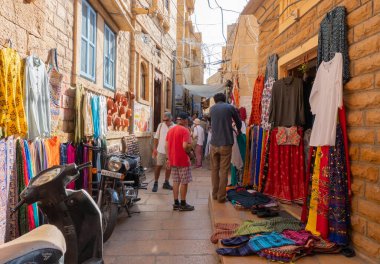 Jaisalmer, Rajasthan, Hindistan - 13 Ekim 2019: Jaisalmer Kalesi veya Altın Kale 'nin içindeki pazar yerindeki yabancılara sabah vakti renkli giysiler satılıyor. UNESCO dünya mirası sahası.