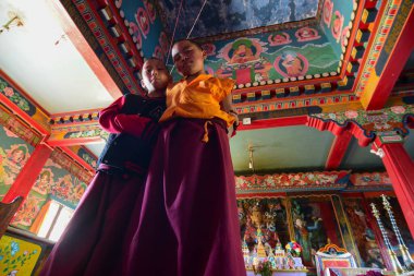 Rinchenpong, Sikkim, Hindistan - 17 Ekim 2016: Rinchenpong Manastırı 'nda duvarları süslenmiş iki genç Lamas fotoğrafçıyı namaz kılarken izliyor. Aşağıdan ateş edilmiş..