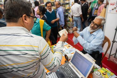 KOLKATA, INDIA - 9 Şubat 2018: Kolkata kitap fuarında eski bir erkek satıcıdan kitap satın alan müşteri. Dünya 'nın en büyük, en katılımcı ve en ünlü ticaret dışı kitap fuarıdır..