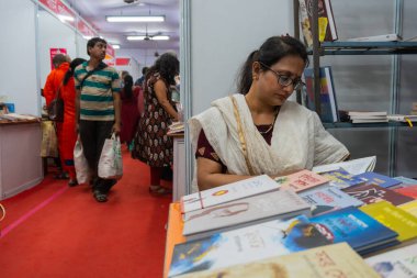 KOLKATA, INDIA - 9 Şubat 2018: Kolkata kitap fuarından önce kitap satın almadan önce kitap okuyan güzel genç Bengali kitap sever kadın. Dünyanın en büyük ve ünlü ticaret dışı kitap fuarıdır..