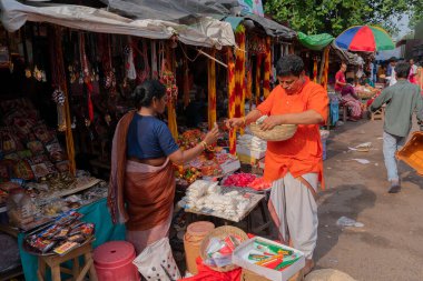 Kolkata, Batı Bengal, Hindistan - 15 Nisan 2019: Genç Bengalli kadın Kalighat tapınağına giden yolda bir erkeğe ibadet malzemeleri satıyor. Görüntü: Kalighat Caddesi, Kolkata.