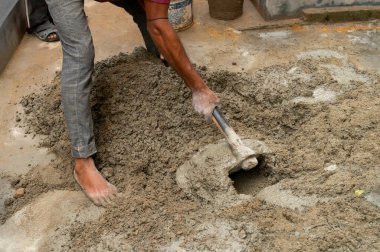 Kolkata, Batı Bengal, Hindistan - 6 Ocak 2020: Yerdeki çimento ve suyu elle karıştıran Hint işçiler. Stcok resmi.