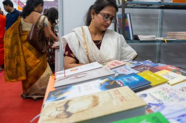 KOLKATA, INDIA - 9 Şubat 2018: Kolkata kitap fuarından önce kitap satın almadan önce kitap okuyan güzel genç Bengali kitap sever kadın. Dünyanın en büyük ve ünlü ticaret dışı kitap fuarıdır..