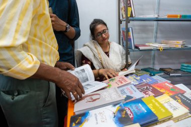 KOLKATA, INDIA - 9 Şubat 2018: Kolkata kitap fuarından önce kitap satın almadan önce kitap okuyan güzel genç Bengali kitap sever kadın. Dünyanın en büyük ve ünlü ticaret dışı kitap fuarıdır..