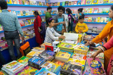 KOLKATA, INDIA - 9 Şubat 2018: Genç Bengalli kız kitaplarını Kolkata kitap fuarında renkli bir kitapçıda satın alıyor. Dünya 'nın en büyük, en katılımcı ve en ünlü ticaret dışı kitap fuarıdır..
