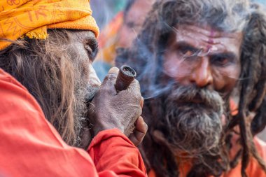 BABUGHAT, KOLKATA, BEST BENGAL / INDIA - 10 HAZİRAN 2015: Hindu Sadhu marihuana içerken, başka bir Sadhu ona bakıyor, yerel olarak Ganja, bir tür kanabis sativa .