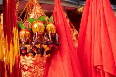 Hindistan 'da Kalighat, Kolkata, Kolkata, Batı Bengal' de üzerinde Hindu kırmızı sembolleri bulunan küçük altın bakır kovalar, ilahi iplerle bağlanmış hindistancevizleri ve kırmızı renkli koltuklar satılıyor..