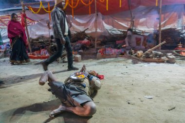 BABUGHAT, KOLKATA, BEST BENGAL / INDIA - 9 HAZİRAN 2018: Gangasagar transit kampında ziyaretçilere yalvaran bir engelli. Kışın renkli ışıkta çekilen.
