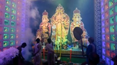 Howrah, Batı Bengal, Hindistan - 5 Ekim 2019: Kansor ghonta çaldı ve Hatpakha sallanırken Hindu purrohit Durga, Durga sondhya aarti 'nin Durga Puja festivalinde giyinmesi için ayna sundu.