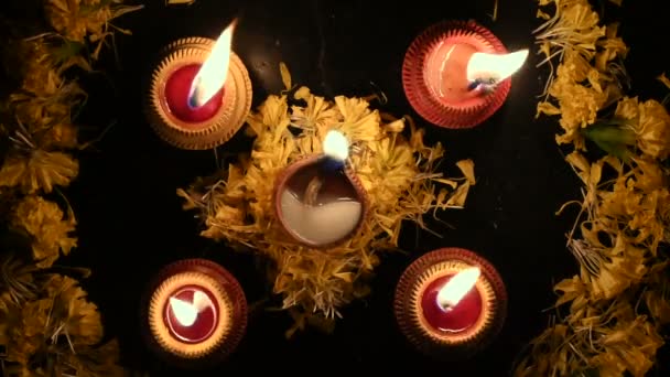 ランゴリの花とその横にある4つのキャンドルやダイヤのトップビュー ディープバリの夜のライト 暗い背景ストック映像 — ストック動画