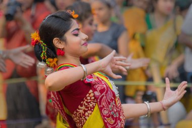 KOLKATA, INDIA - 12 Mart 2017: Sarı ve kırmızı sari (geleneksel Hint elbisesi) ve dol / holi festivalinde dans eden kız dansçının dans pozu.