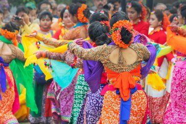 Kolkata, Hindistan - 1 Mart 2018: Renkli sari (geleneksel Hint elbisesi) ve Palash çiçekleri (Butea monosperma) giymiş kız dansçılar, Dol (Bengalce) veya Holi (Hintçe) festivalinde dans ediyorlar..